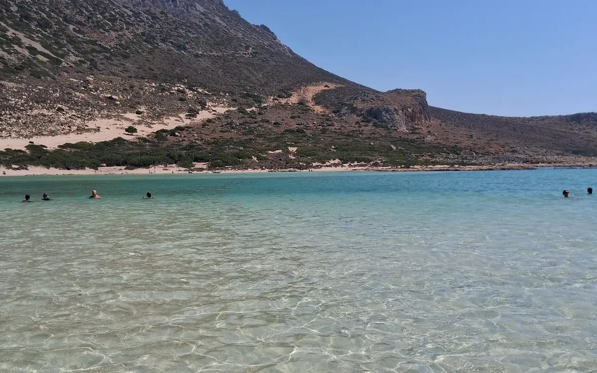 Clear shallow water over sand with dry hills behind