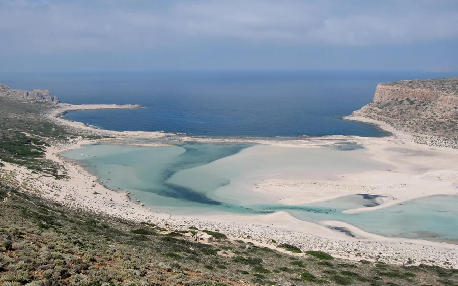 Pale sand and shallow water of the lagoon below a rocky headland