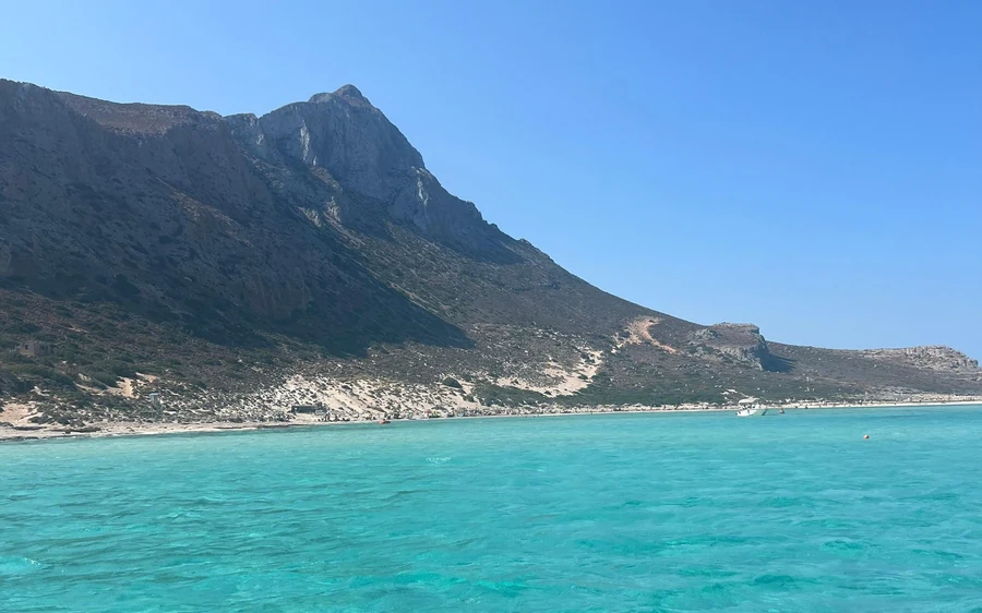Turquoise water at the foot of a steep, bare mountain